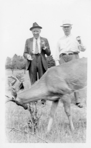 Nester and Covey family - two men smoking cigars in front of a deer eating grass